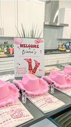 pink hats and placemats are sitting on the counter in front of a welcome sign