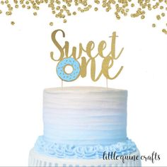 a blue and white cake with gold sprinkles on top that says sweet one