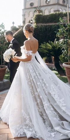 a bride and groom are walking down the street together in front of a building with a clock tower