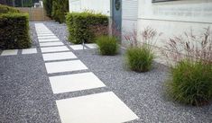 an outdoor walkway is lined with gravel and grass