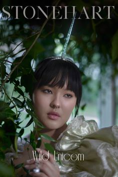 a woman in a white dress is holding onto some leaves and looking at the camera