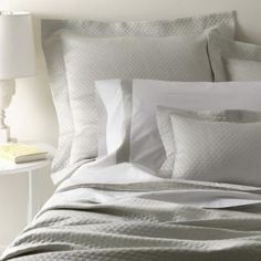 a bed with white sheets and pillows on top of it next to a night stand