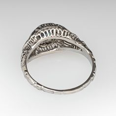 an antique style ring with filigrees and leaves on the sides, set in white gold