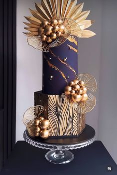 a three - tiered cake with gold decorations on it's sides and purple icing