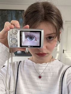 a young woman holding up a camera to take a photo with an eyeball in front of her face