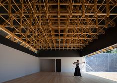 a woman standing in an empty room with wooden beams on the ceiling