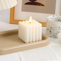 a lit candle sitting on top of a tray next to a cup