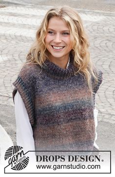 a woman standing on the street wearing a knitted sweater and smiling at the camera