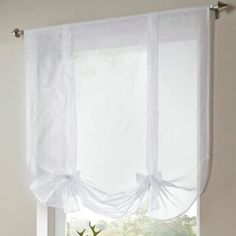 a window with white sheer curtains and deer heads on the windowsill in front of it