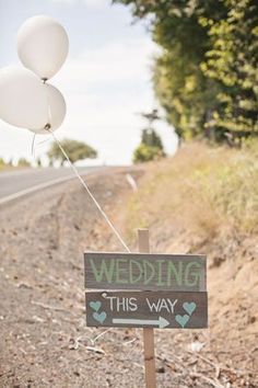 a wooden sign with balloons attached to it