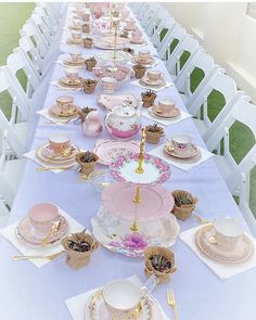 a long table is set with pink and white dishes, cups, and saucers