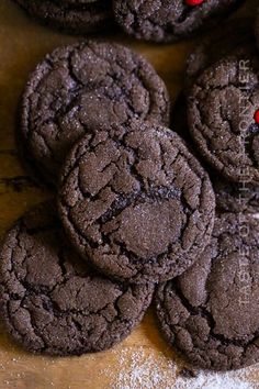 chocolate cookies with red frosting and sprinkles on a wooden table top