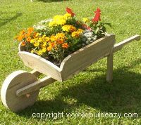 a wooden planter filled with flowers on top of green grass next to a bench