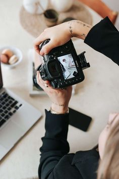 a person holding up a camera in front of a laptop