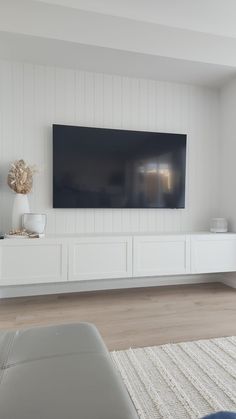 a large flat screen tv mounted to the side of a white wall in a living room