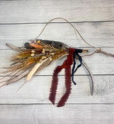 an assortment of dried feathers on a white wooden background with twine and ribbon tied around the ends