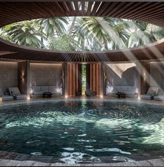 an indoor swimming pool with lounge chairs and palm trees in the backgrouds