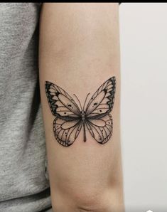 a woman's arm with a black and white butterfly tattoo on the left forearm