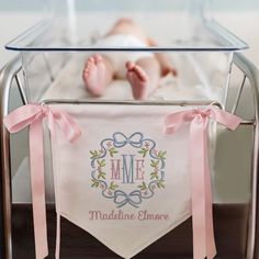 a baby laying in a crib next to a pink ribbon