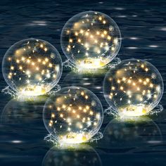 three bubbles with lights floating in the water and snow flakes all around them on top of each other