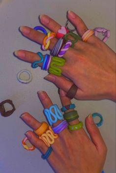 two hands holding different colored rings on top of a white surface with letters and numbers painted on them