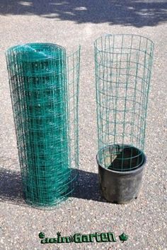 two green wire baskets sitting next to each other on the ground near a potted plant