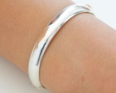 Most bangles are circular in shape , they are symbolic of planet Jupiter , Mercury , and the moon.  A truly classic piece, made of sterling silver. Modern, minimalist oval shape, it has a smooth inner making it a comfort fit bangle . The sides can be opened / closed on a pin hinge and puss-in latch for taking off and putting on.    The shape, weight and smooth finish of this bangle makes it lovely and tactile. Suitable for all occasions formal or otherwise and will complement any wardrobe. "This Sterling Silver Jewelry With Shiny Finish, Sterling Silver Jewelry With Shiny Round Band, Classic Sterling Silver Bracelet With Polished Finish, White Gold Polished Bangle, White Gold Bangle With Polished Finish, White Gold Polished Round Bangle, Silver Bangle With Sterling Silver Clasp, Bangle With Sterling Silver Clasp, Classic Round Bangle Stamped 925