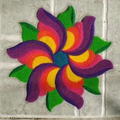 a colorful flower painted on the side of a white tile wall next to a person's hand