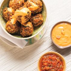 two bowls filled with meatballs and sauce on top of a white wooden table next to another bowl