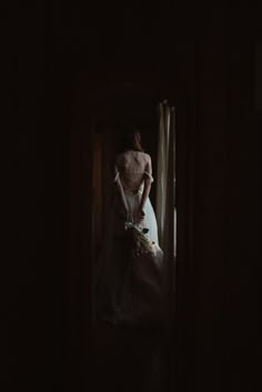 a woman in a wedding dress looking out the window