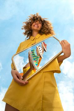 a woman is holding a mirror with her reflection in it and smiling at the camera