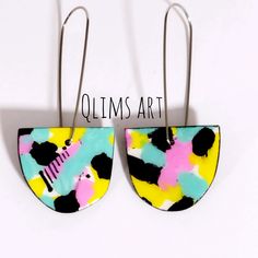 two pairs of earrings with colorful designs hanging from hooks on a white background that says olims art