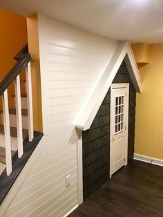 an empty room with stairs and a dog house on the wall next to the door