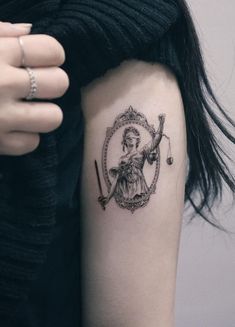 a lady justice tattoo on the left upper arm