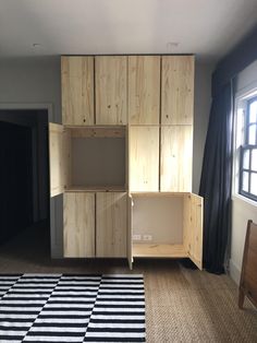 an empty room with wooden cabinets and black and white rug