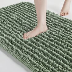 a person standing on top of a green rug next to a persons foot in the floor