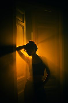 a woman standing next to a window in the dark