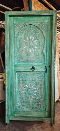 an old green door with intricate carvings on the front and side panels, in a warehouse