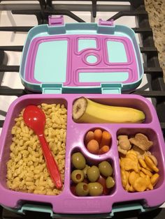 a purple lunch box filled with food on top of a stove burner next to a red spoon