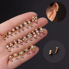 the gold ear studs are being held in someone's hand with their measurements