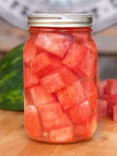 a jar filled with watermelon slices on top of a wooden table