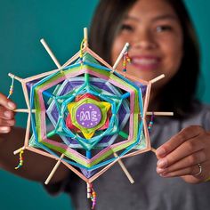 a girl holding up a colorful object made from sticks