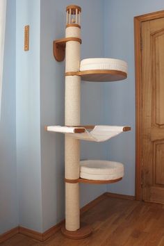 a cat tree in the corner of a room with blue walls and hardwood floors,