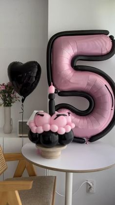 a pink and black number five balloon sitting on top of a table next to a vase