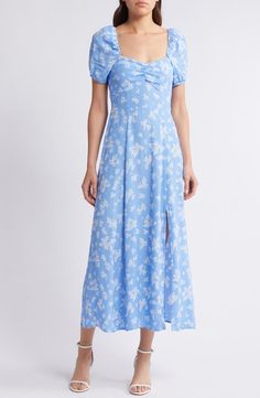 a woman is wearing a blue dress with white flowers on it and she has her hands in her pockets