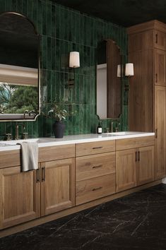 a bathroom with two sinks, mirrors and green tiled walls in it's center