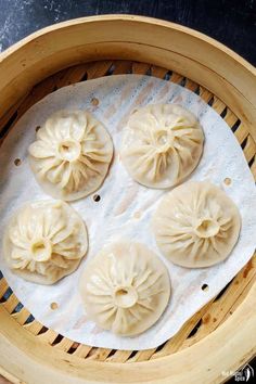 four dumplings in a bamboo steamer basket