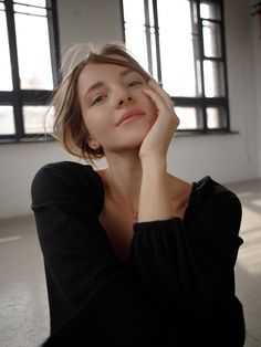 a woman sitting on the floor with her hand under her chin