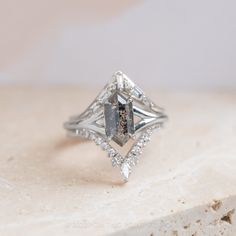 a diamond ring sitting on top of a white stone slab with diamonds surrounding it and the center stone in the middle