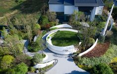 an aerial view of a house with circular garden design in the front yard and driveway